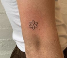 a woman's arm with a small flower tattoo on the left side of her arm