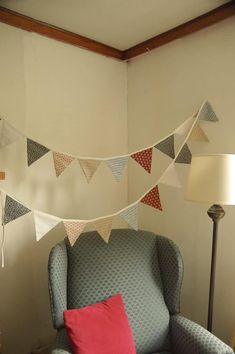 a living room with a chair, lamp and bunting flags hanging from the ceiling