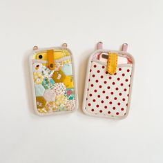 two cell phones are next to each other on a white surface with red and yellow polka dots