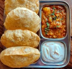 a lunch box with rolls, dip and sauce on the side is ready to be eaten