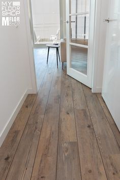 an open door leading to a living room with wood flooring and white painted walls