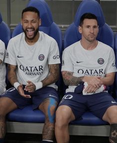 three soccer players are sitting on the bench and smiling at the camera while wearing matching jerseys