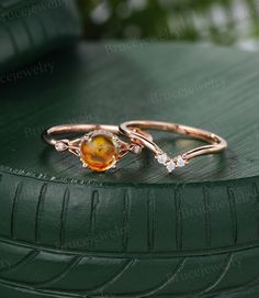 two gold rings sitting on top of a green tire treading surface, with an orange and white stone in the middle