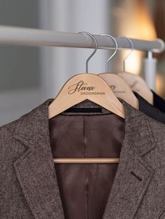 a suit and tie hang on a wooden hanger in front of a mirror with the name henry groomman