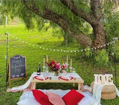 a picnic table set up in the middle of a field with candles and flowers on it