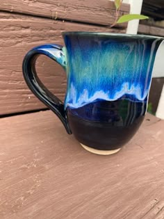 a blue and black coffee cup sitting on top of a wooden table