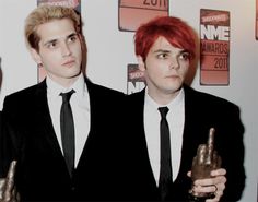 two young men in suits and ties holding up their trophies at an awards event,