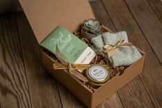 an open box with some items in it on a wooden floor next to a candle