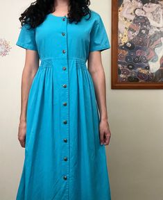 Brand: Regatta Sport Size: Marked a size 12 Bust: 51cm Waist: 45cm Skirt Length: 87cm Fabric: 100% Cotton Features: Button up front, smocking on waist and drawstring tie on back waist. Cotton Midi Dress With Buttons, Blue Button-up Cotton Midi Dress, Blue Cotton Button-up Midi Dress, Casual Button-up Pleated Midi Dress, Summer Workwear Vintage Dress With Buttons, Summer Vintage Dress For Work With Buttons, Casual Blue Vintage Dress With Short Sleeves, Casual Fitted Vintage Dress With Buttons, Knee-length Vintage Dress With Buttons For Daywear