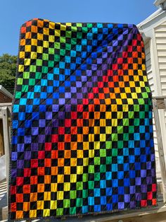 a multicolored quilt hanging on the side of a house