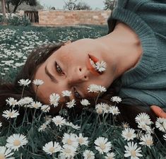 a woman laying in the grass with daisies