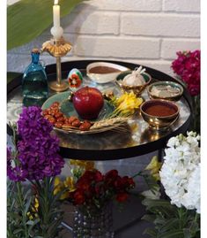 an assortment of food is displayed on a table with flowers in vases and candles