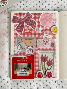 an open notebook with various stickers on the pages and in front of it is a red checkered background