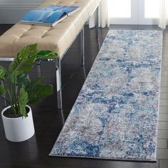 a blue and white area rug with a bench in the corner next to it on a hard wood floor