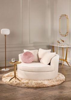 a living room with white furniture and pink pillows on the chair, gold side tables