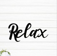 the word relax is written in black ink on a white wood background with flowers and greenery