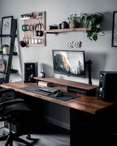 a desk with a computer and speakers on it in front of a wall mounted shelf