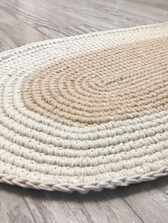 an oval rug on the floor with white and beige colors, in front of a wooden floor