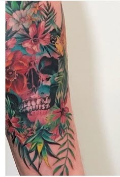 a colorful skull with flowers and leaves on it's arm is seen in this image