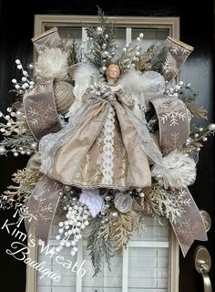 a christmas wreath with an angel on the front door and snowflakes around it