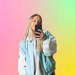 a woman taking a selfie in front of a rainbow colored background with her phone