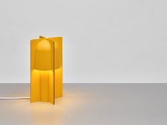 a yellow lamp sitting on top of a table next to a white wall and floor