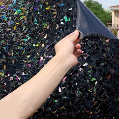 a hand is holding an umbrella over a mosaic tile wall in front of a house