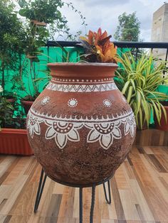 a large pot sitting on top of a metal stand next to a planter filled with flowers