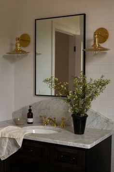 a bathroom sink with a mirror above it and flowers in a vase on the counter