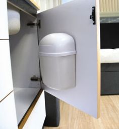 a white toilet sitting inside of a bathroom next to a wooden floor and cabinet door