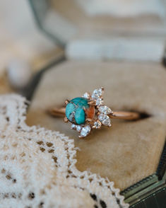 A close up image showing the "Aurae" engagement ring from Staghead Designs. This 14K rose gold ring features asymmetrical floral diamond accents made up of marquise and round diamonds around a round cabochon cut spiny oyster turquoise. Spiny oyster turquoise is a composite stone made up of turquoise, pyrite, and orange spiny oyster shell. Western Wedding Rings, Turquoise Engagement Ring, Turquoise Wedding Rings, Turquoise Wedding Band, Spiny Oyster Turquoise, Turquoise Ring Engagement, Oyster Turquoise, 14k Gold Engagement Ring, Staghead Designs