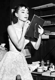 a black and white photo of a woman in a dress looking at something on a clipboard