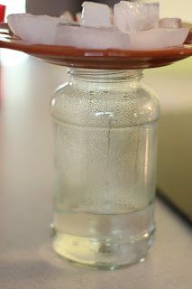 a glass jar with ice cubes on it sitting on top of a wooden tray