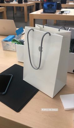 a white shopping bag sitting on top of a table next to a black mouse pad