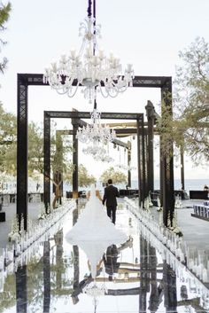 the bride and groom are walking down the aisle at their wedding ceremony with chandeliers hanging from the ceiling