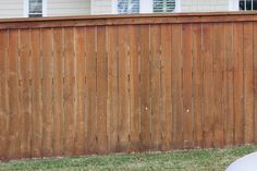 a white frisbee sitting in the grass next to a wooden fence and house