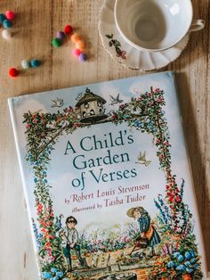 a child's garden of verses by robert louis stevens is on the table next to a cup and saucer