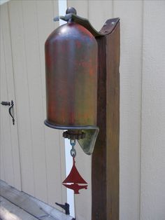 an old fashioned metal bell hanging from the side of a building with a chain attached to it