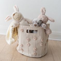 two stuffed animals are sitting in a storage basket on the floor next to each other