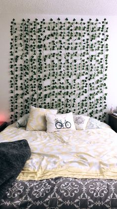 a bed with white and yellow comforter in front of a decorative headboard that has green vines on it