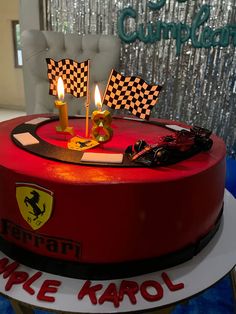 a red cake with two racing flags on top and candles in the shape of cars