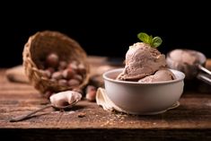 a bowl filled with ice cream sitting on top of a wooden table next to nuts