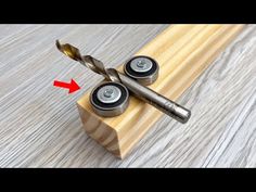 two screws are attached to the end of a piece of wood with an arrow pointing up