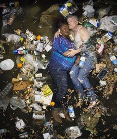 two women hugging in the water surrounded by trash