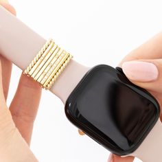 a woman is holding onto an apple watch with gold bracelets on her wrist,