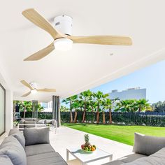 a living room with couches, tables and a ceiling fan in the middle of it