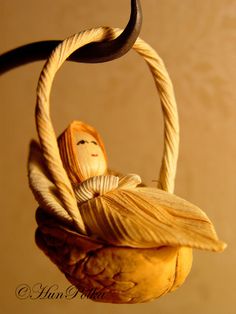 a wooden doll hanging from a rope in the shape of a basket