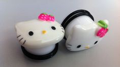 two hello kitty hair clips are shown on a white surface, one has a pink bow and the other has a green bow