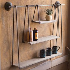 two shelves with cups and bottles on them in front of a wall mounted potted plant