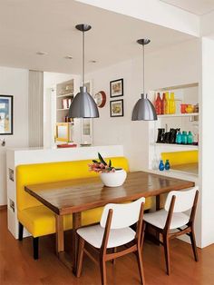 a dining room table with two chairs and a yellow bench in front of the table